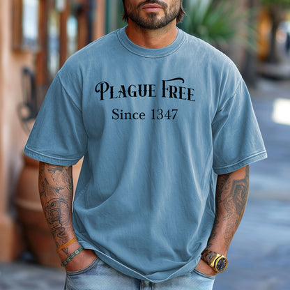 Person wearing a Washed Denim T-shirt with a humorous Renaissance Faire design that reads “Plague Free Since 1347” in medieval-style lettering, celebrating fair and festival fun with a nod to history. A playful shirt perfect for history buffs, medieval enthusiasts, and anyone attending a Renaissance fair or themed event.