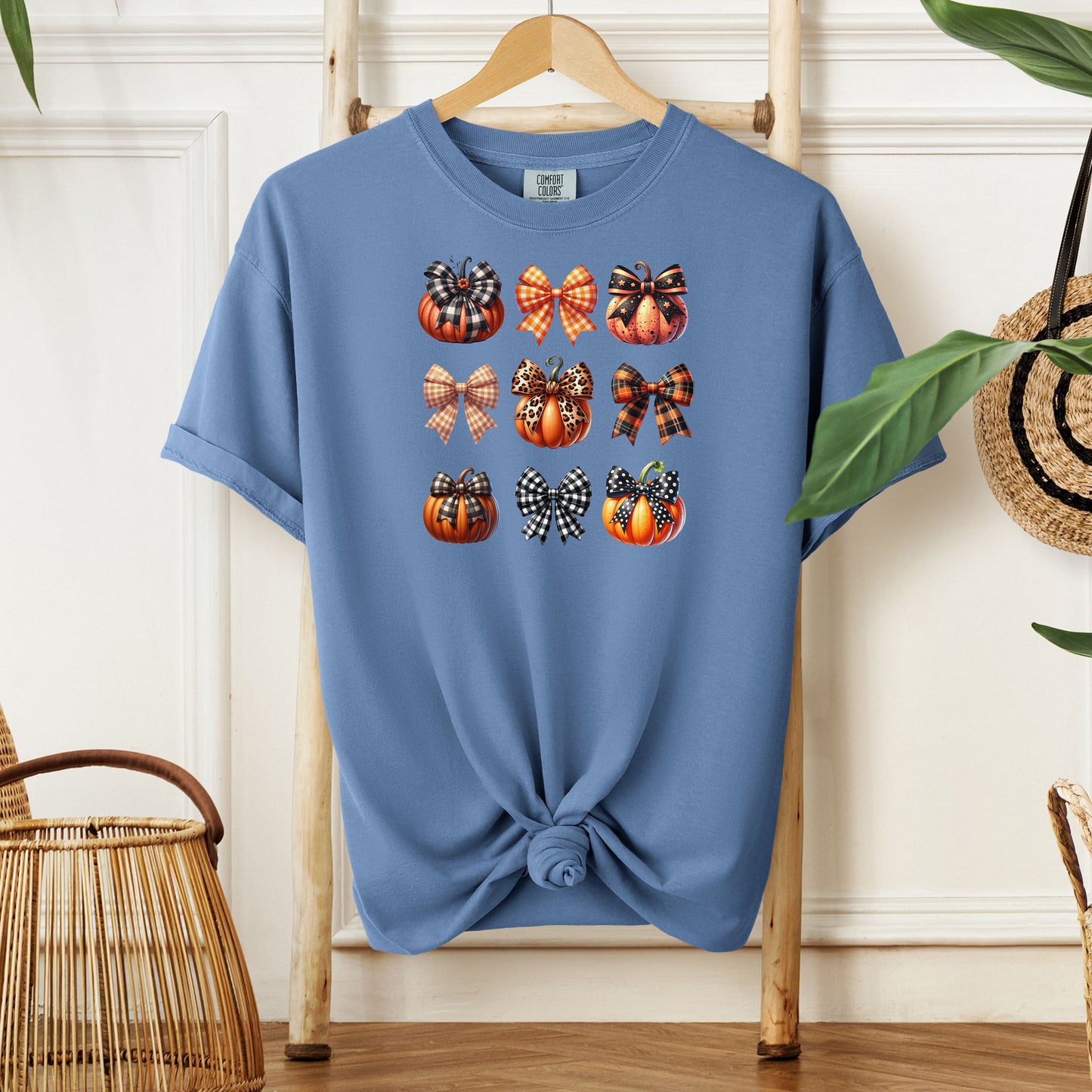 Washed Denim T-shirt featuring “Pumpkins and Coquette Bows” design. The artwork displays a grid of pumpkins and decorative coquette bows in plaid, gingham, and fall patterns, blending rustic autumn charm with a playful coquette aesthetic. Perfect for celebrating fall fashion and cozy seasonal vibes with a cute, stylish twist.