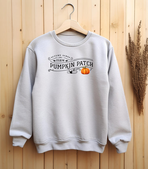 Ash Gildan sweatshirt featuring a vintage-inspired black “Autumn Acres Farm Pumpkin Patch” design with decorative swirls and white, black and orange pumpkins—on the side. A cozy, rustic fall look perfect for pumpkin picking, hayrides, and seasonal outings.