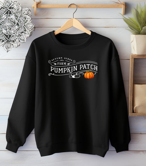 Black Gildan sweatshirt featuring a vintage-inspired white “Autumn Acres Farm Pumpkin Patch” design with decorative swirls and white, black, and orange pumpkins—on the side. A cozy, rustic fall look perfect for pumpkin picking, hayrides, and seasonal outings.