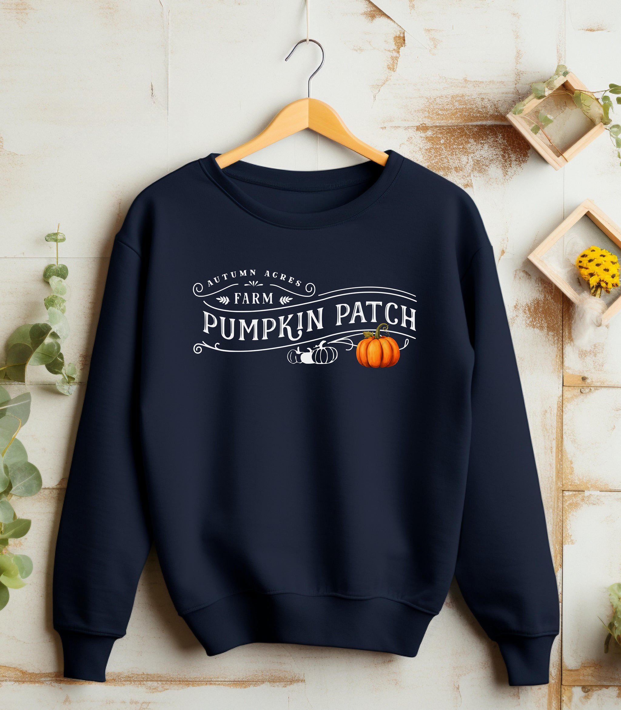 Navy Gildan sweatshirt featuring a vintage-inspired white “Autumn Acres Farm Pumpkin Patch” design with decorative swirls and white and orange pumpkins—on the side. A cozy, rustic fall look perfect for pumpkin picking, hayrides, and seasonal outings.