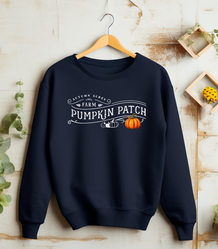 Navy Gildan sweatshirt featuring a vintage-inspired white “Autumn Acres Farm Pumpkin Patch” design with decorative swirls and white and orange pumpkins—on the side. A cozy, rustic fall look perfect for pumpkin picking, hayrides, and seasonal outings.