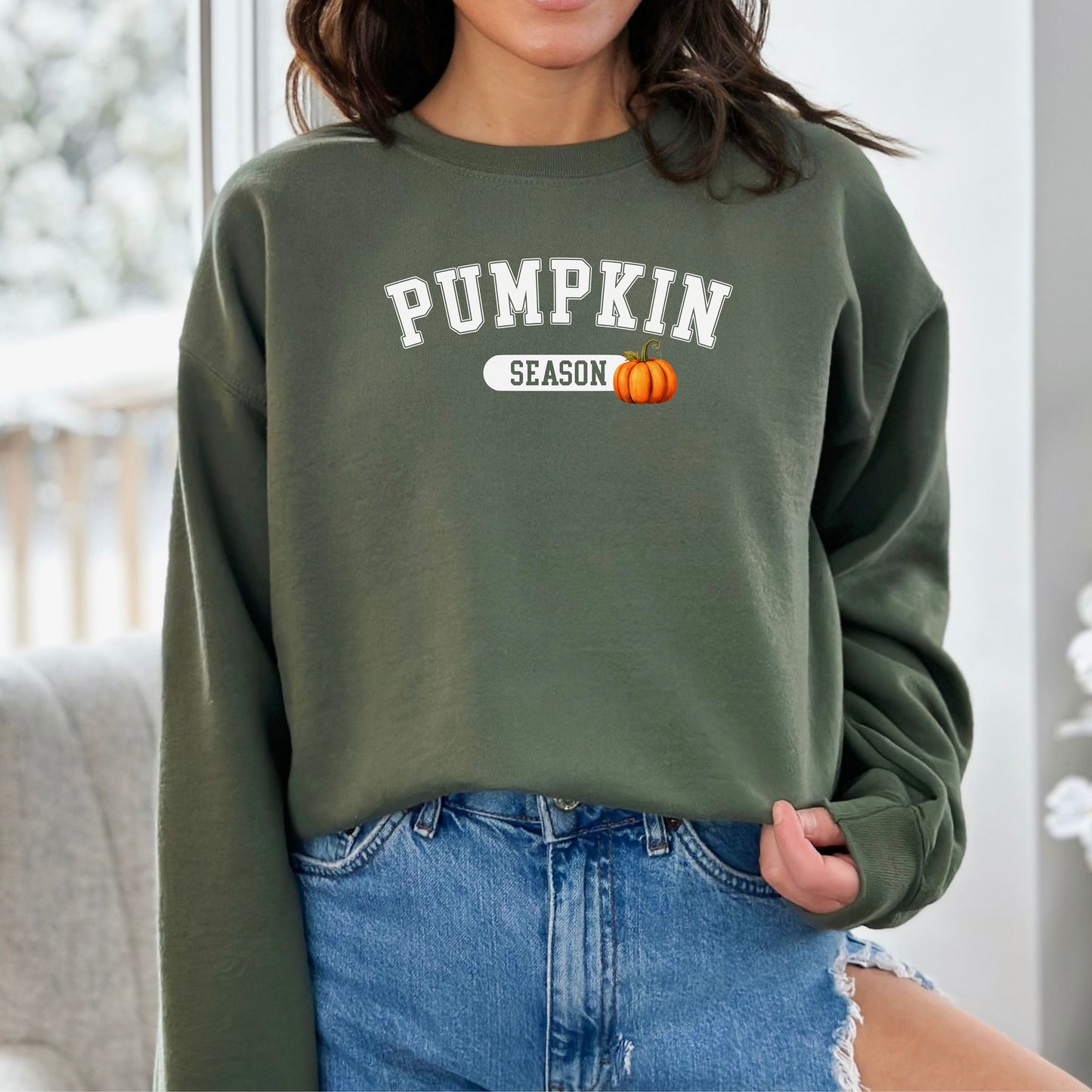 Person wearing a military green sweatshirt with 'Pumpkin Season' text and pumpkin graphic.