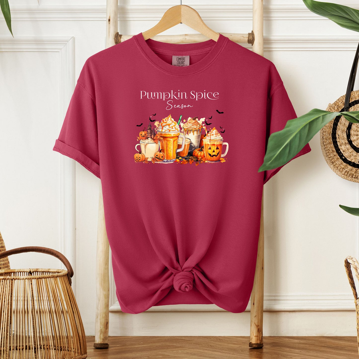 Chili T-shirt featuring a “Pumpkin Spice Season” design with colorful autumn drinks topped with whipped cream, surrounded by pumpkins, jack-o’-lanterns, fall leaves, and flying bats. The cozy, festive artwork celebrates the love for pumpkin spice and autumn vibes, perfect for seasonal wear and fall enthusiasts.