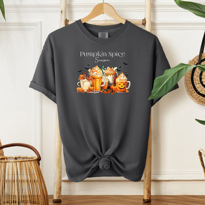 Pepper T-shirt featuring a “Pumpkin Spice Season” design with colorful autumn drinks topped with whipped cream, surrounded by pumpkins, jack-o’-lanterns, fall leaves, and flying bats. The cozy, festive artwork celebrates the love for pumpkin spice and autumn vibes, perfect for seasonal wear and fall enthusiasts.