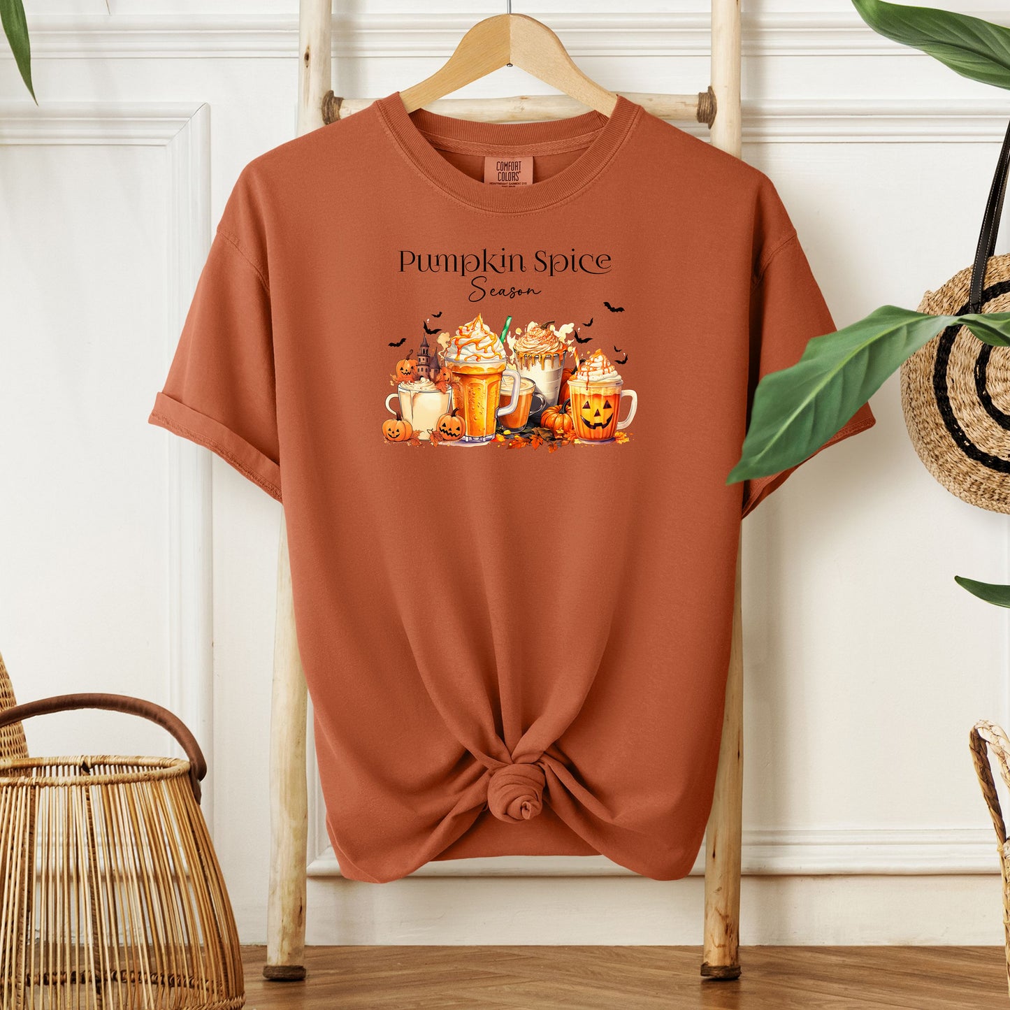 Yam T-shirt featuring a “Pumpkin Spice Season” design with colorful autumn drinks topped with whipped cream, surrounded by pumpkins, jack-o’-lanterns, fall leaves, and flying bats. The cozy, festive artwork celebrates the love for pumpkin spice and autumn vibes, perfect for seasonal wear and fall enthusiasts.