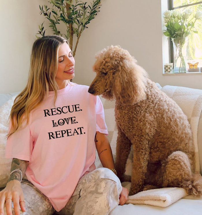 Rescue. Love. Repeat. T-shirt with bold black typography and cute kitten and puppy accents inside the letters. Shown on a blossom pink unisex tee, this design is perfect for animal rescue advocates, pet lovers, and adoption supporters. Ideal for wearing to volunteer events, shelter fundraisers, or everyday outings to show pride in rescuing and loving animals.