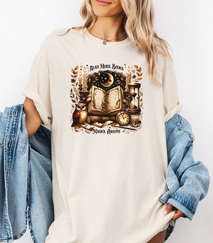 Person wearing an ivory t-shirt featuring a whimsical "Read More Books, Magick Awaits" design. The graphic showcases an open enchanted book surrounded by candles, a crescent moon, owl, pocket watch, hourglass, and magical elements, creating a mystical and literary aesthetic perfect for book lovers and fantasy fans.