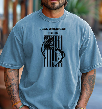 Reel American Pride T-shirt featuring a bold fishing-themed design with the phrase 'Reel American Pride' above an American flag graphic. A large fish is hooked on a fishing line overlaying the flag’s stripes. Printed on a washed denim unisex tee, this patriotic fishing shirt is perfect for anglers who love both their country and the sport. Ideal for summer outings, fishing trips, or casual everyday wear.