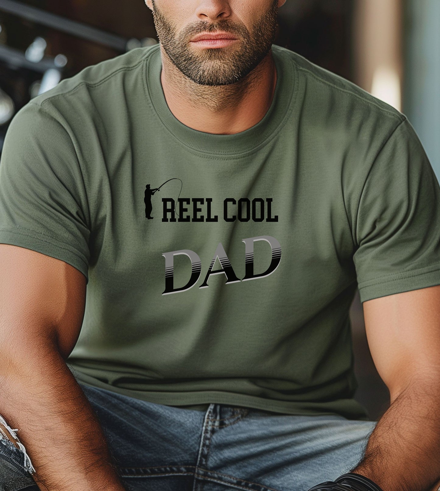 Reel Cool Dad T-shirt featuring a playful fishing-themed design with the phrase 'Reel Cool Dad' and a silhouette of a fisherman casting a line. Printed on a moss unisex tee, this fun graphic is perfect for dads who love fishing and spending time outdoors. Ideal for Father’s Day, birthdays, or casual wear for the proud angler dad.