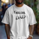 Reel Cool Dad T-shirt featuring a playful fishing-themed design with the phrase 'Reel Cool Dad' and a silhouette of a fisherman casting a line. Printed on a classic white unisex tee, this fun graphic is perfect for dads who love fishing and spending time outdoors. Ideal for Father’s Day, birthdays, or casual wear for the proud angler dad.