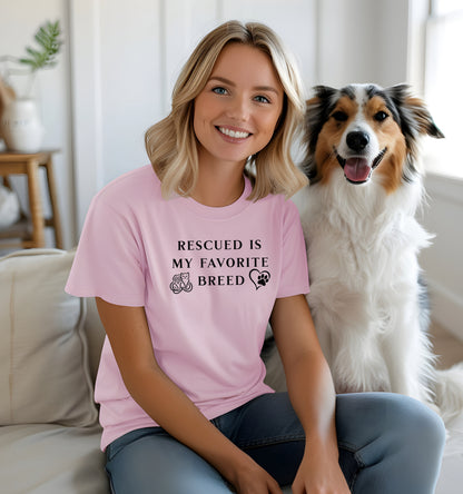 Rescued Is My Favorite Breed T-shirt featuring bold black text with small graphics of a cat, dog, and paw print heart. Printed on a Pink unisex tee, this design is perfect for animal lovers and rescue advocates. Ideal for showcasing pride in adopting pets and supporting animal rescue efforts, whether worn casually or at adoption events.