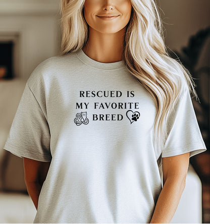 Rescued Is My Favorite Breed T-shirt featuring bold black text with small graphics of a cat, dog, and paw print heart. Printed on a ash unisex tee, this design is perfect for animal lovers and rescue advocates. Ideal for showcasing pride in adopting pets and supporting animal rescue efforts, whether worn casually or at adoption events.