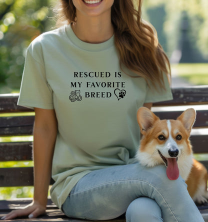 Rescued Is My Favorite Breed T-shirt featuring bold black text with small graphics of a cat, dog, and paw print heart. Printed on a sage unisex tee, this design is perfect for animal lovers and rescue advocates. Ideal for showcasing pride in adopting pets and supporting animal rescue efforts, whether worn casually or at adoption events.