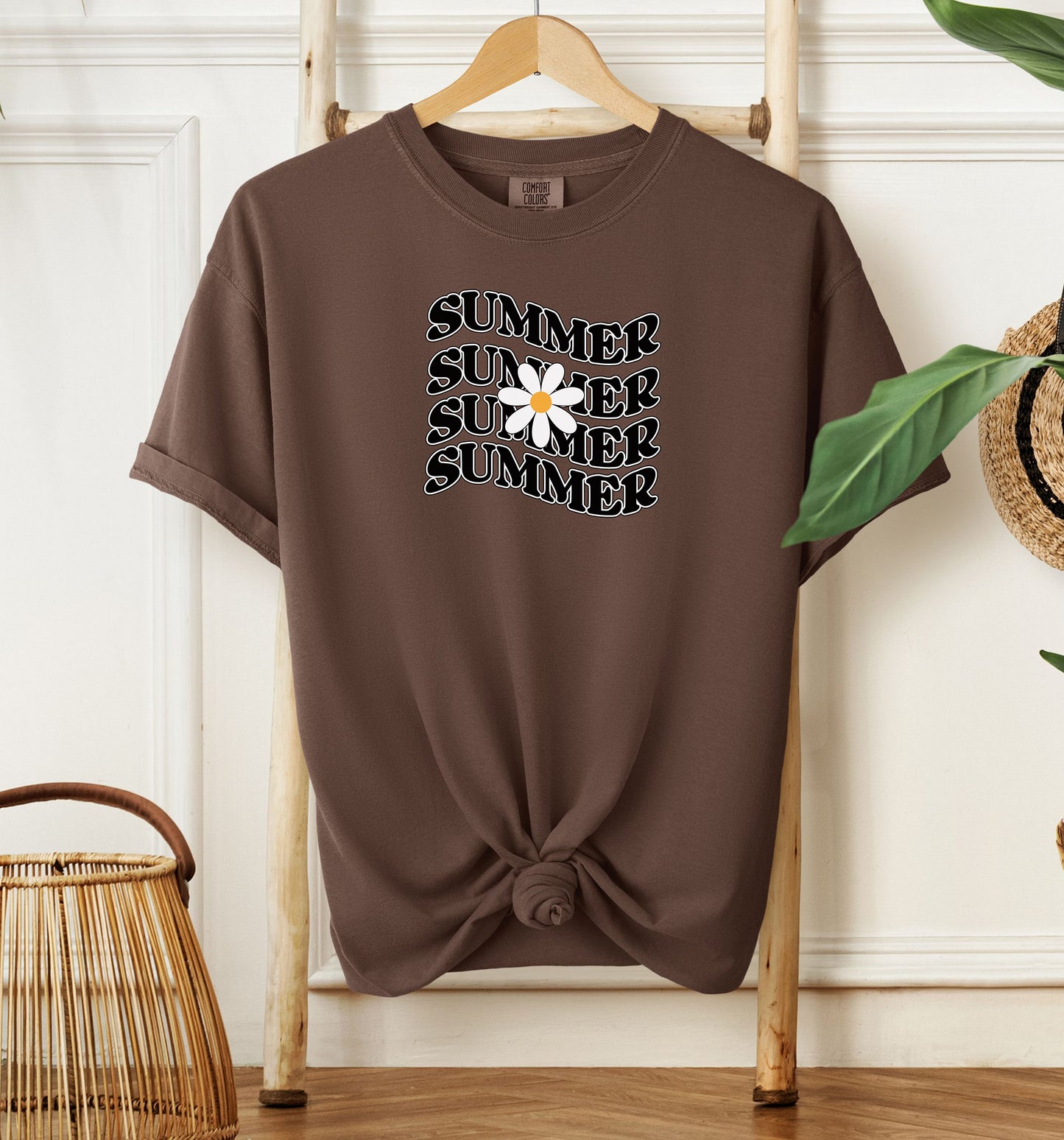 Espresso T-shirt featuring a retro wavy text design that repeats the word “SUMMER” four times in bold black vintage-style letters. A large white daisy with a yellow center overlaps the middle of the design, adding a cheerful floral touch. Perfect for sunny days, vacations, and casual outings, this shirt has a nostalgic, laid-back summer vibe.