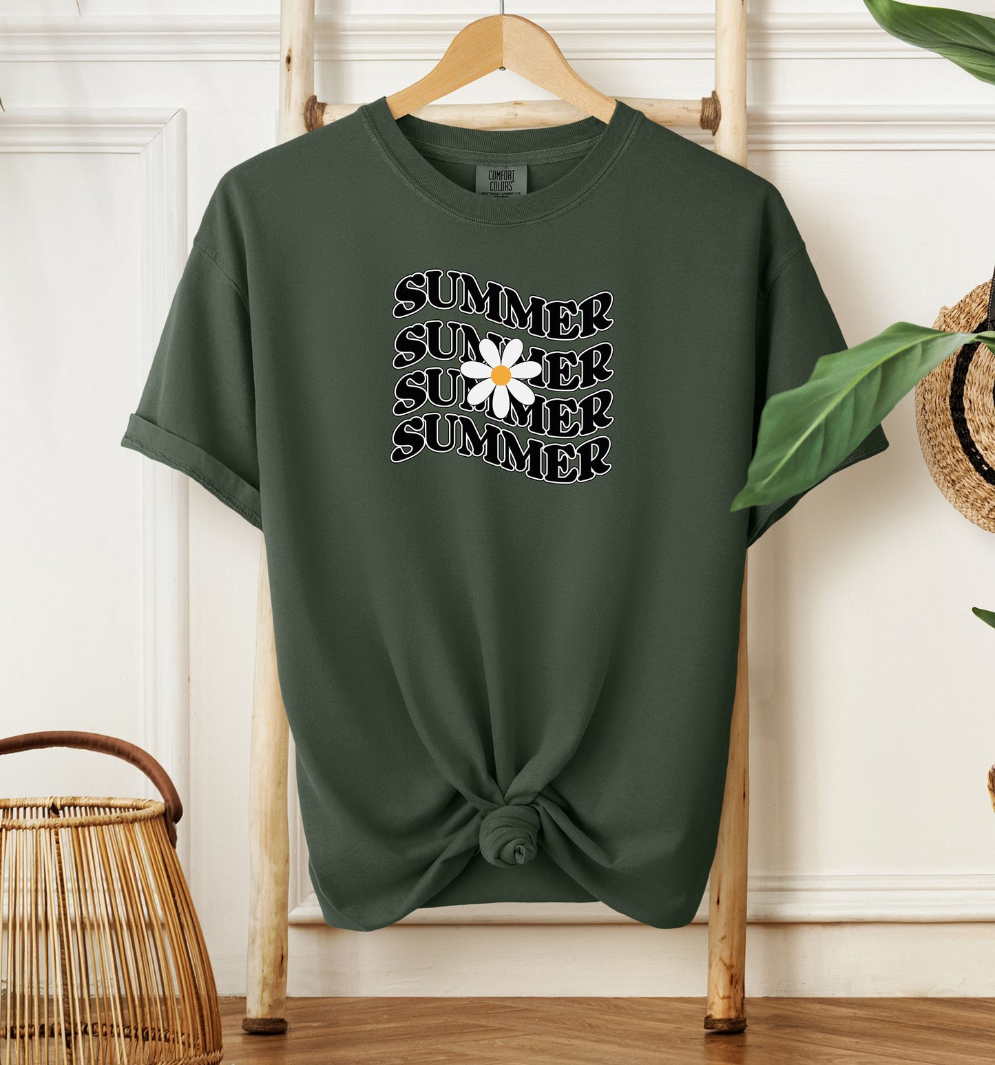 Hemp color T-shirt featuring a retro wavy text design that repeats the word “SUMMER” four times in bold black vintage-style letters. A large white daisy with a yellow center overlaps the middle of the design, adding a cheerful floral touch. Perfect for sunny days, vacations, and casual outings, this shirt has a nostalgic, laid-back summer vibe.
