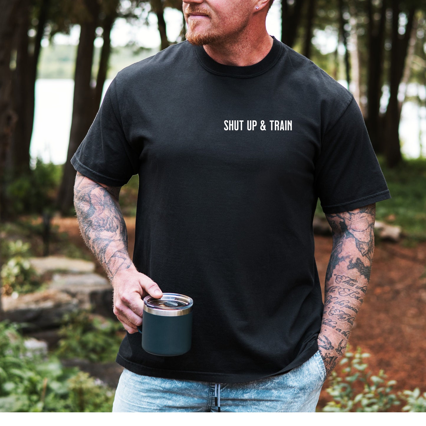 Person wearing a black T-shirt featuring the bold motivational phrase “Shut Up & Train” in black text on the chest. The minimalist design delivers a powerful fitness message, perfect for athletes, bodybuilders, and gym-goers who embrace discipline and dedication in their workouts