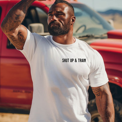 Person wearing a classic white T-shirt featuring the bold motivational phrase “Shut Up & Train” in black text on the chest. The minimalist design delivers a powerful fitness message, perfect for athletes, bodybuilders, and gym-goers who embrace discipline and dedication in their workouts