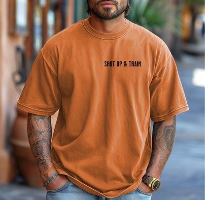 Person wearing a yam T-shirt featuring the bold motivational phrase “Shut Up & Train” in black text on the chest. The minimalist design delivers a powerful fitness message, perfect for athletes, bodybuilders, and gym-goers who embrace discipline and dedication in their workouts