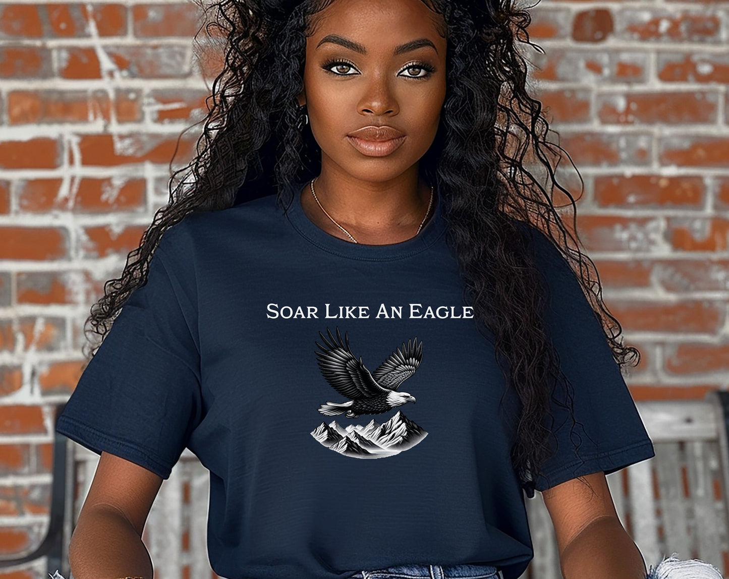 True Navy T-shirt featuring a bold “Soar Like An Eagle” design with white text above a detailed black and white illustration of a soaring eagle over rugged mountain peaks. The graphic captures strength, freedom, and nature’s beauty, making it perfect for outdoor enthusiasts, adventure lovers, and patriotic spirits. Modeled in a casual, relaxed fit for everyday wear.
