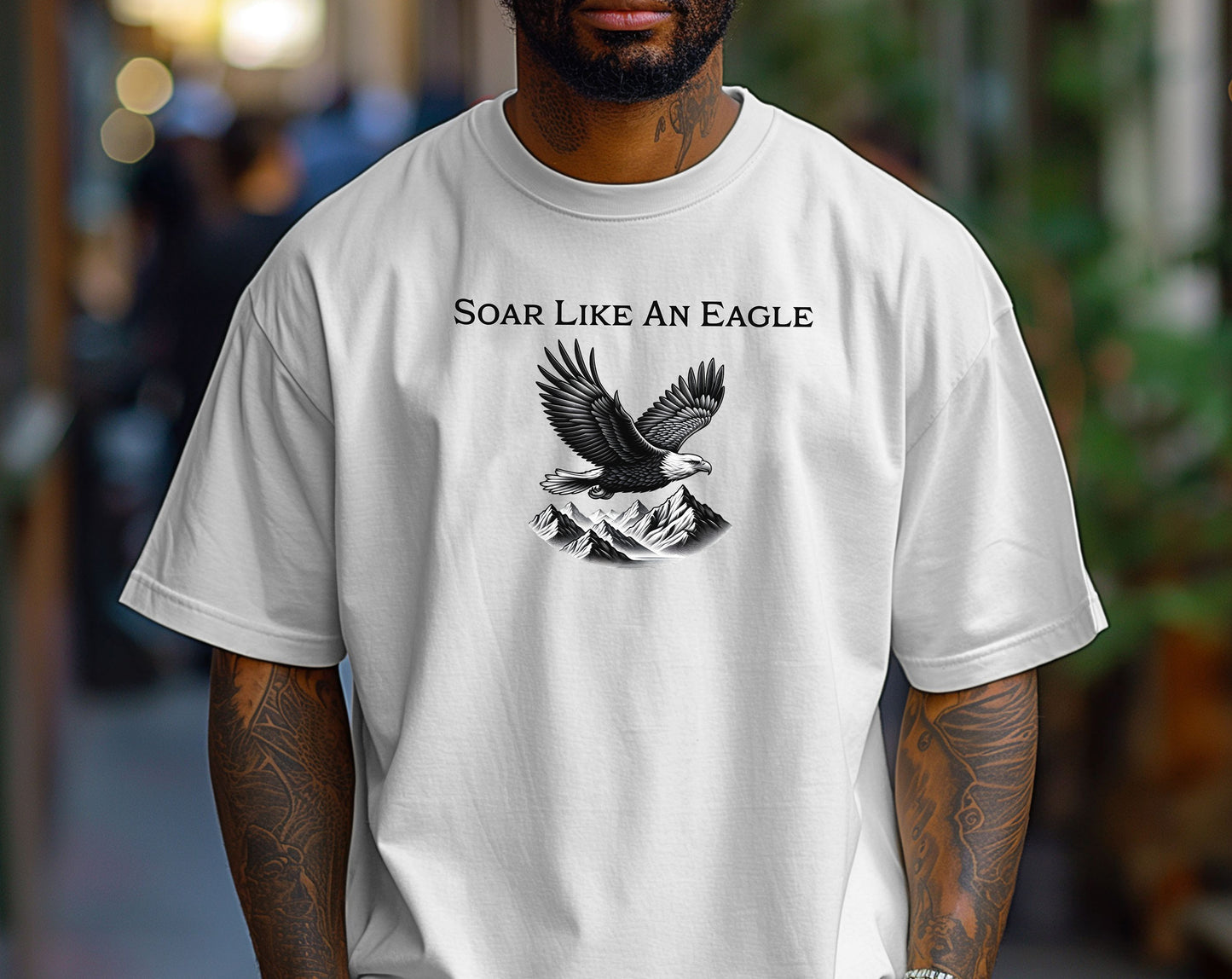 Classic White T-shirt featuring a bold “Soar Like An Eagle” design with white text above a detailed black and white illustration of a soaring eagle over rugged mountain peaks. The graphic captures strength, freedom, and nature’s beauty, making it perfect for outdoor enthusiasts, adventure lovers, and patriotic spirits. Modeled in a casual, relaxed fit for everyday wear.