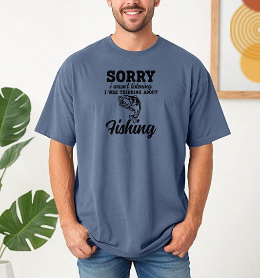 SORRY I wasn’t listening. I was thinking about Fishing' T-shirt featuring bold and script fonts with a detailed fish illustration. Printed on a blue jean unisex tee, this humorous design is perfect for fishing enthusiasts who’d rather be on the water than anywhere else. Ideal for casual wear, fishing trips, or as a fun gift for anglers and dads who love the sport.