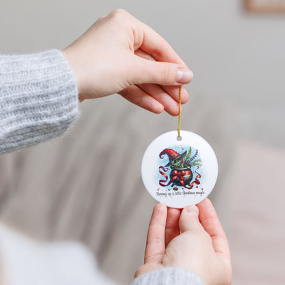 Hand holding a Christmas ornament with a colorful design against a neutral background