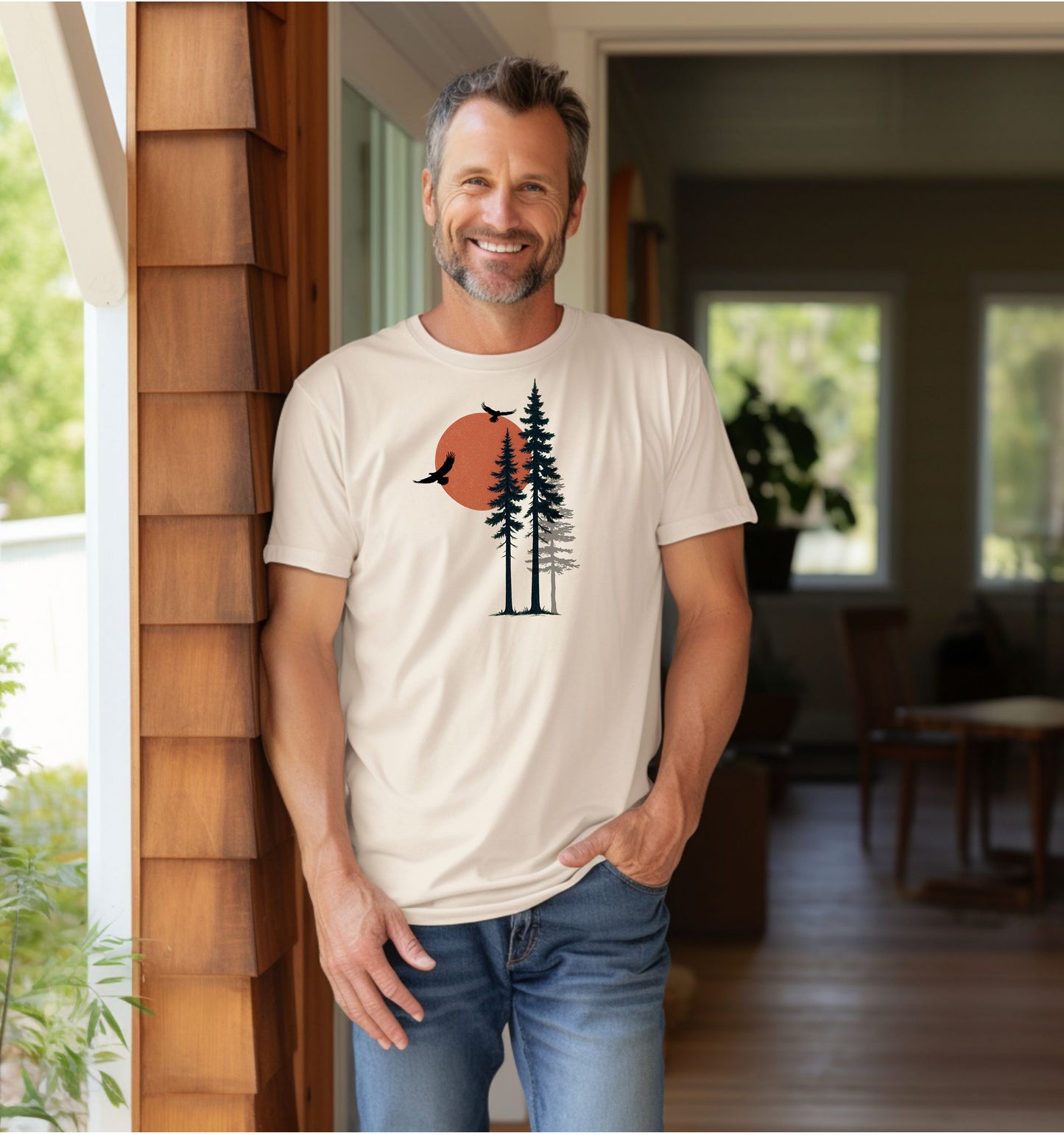 Sunset Pines & Soaring Eagles T-shirt featuring a minimalist nature design with tall pine trees silhouetted against a warm orange sun. Two eagles glide through the sky, adding a touch of wilderness and freedom. Printed on an ivory unisex tee, this nature-inspired graphic is perfect for outdoor lovers, hikers, and those who appreciate serene, scenic beauty.