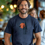 Sunset Pines & Soaring Eagles T-shirt featuring a minimalist nature design with tall pine trees silhouetted against a warm orange sun. Two eagles glide through the sky, adding a touch of wilderness and freedom. Printed on a midnight unisex tee, this nature-inspired graphic is perfect for outdoor lovers, hikers, and those who appreciate serene, scenic beauty.