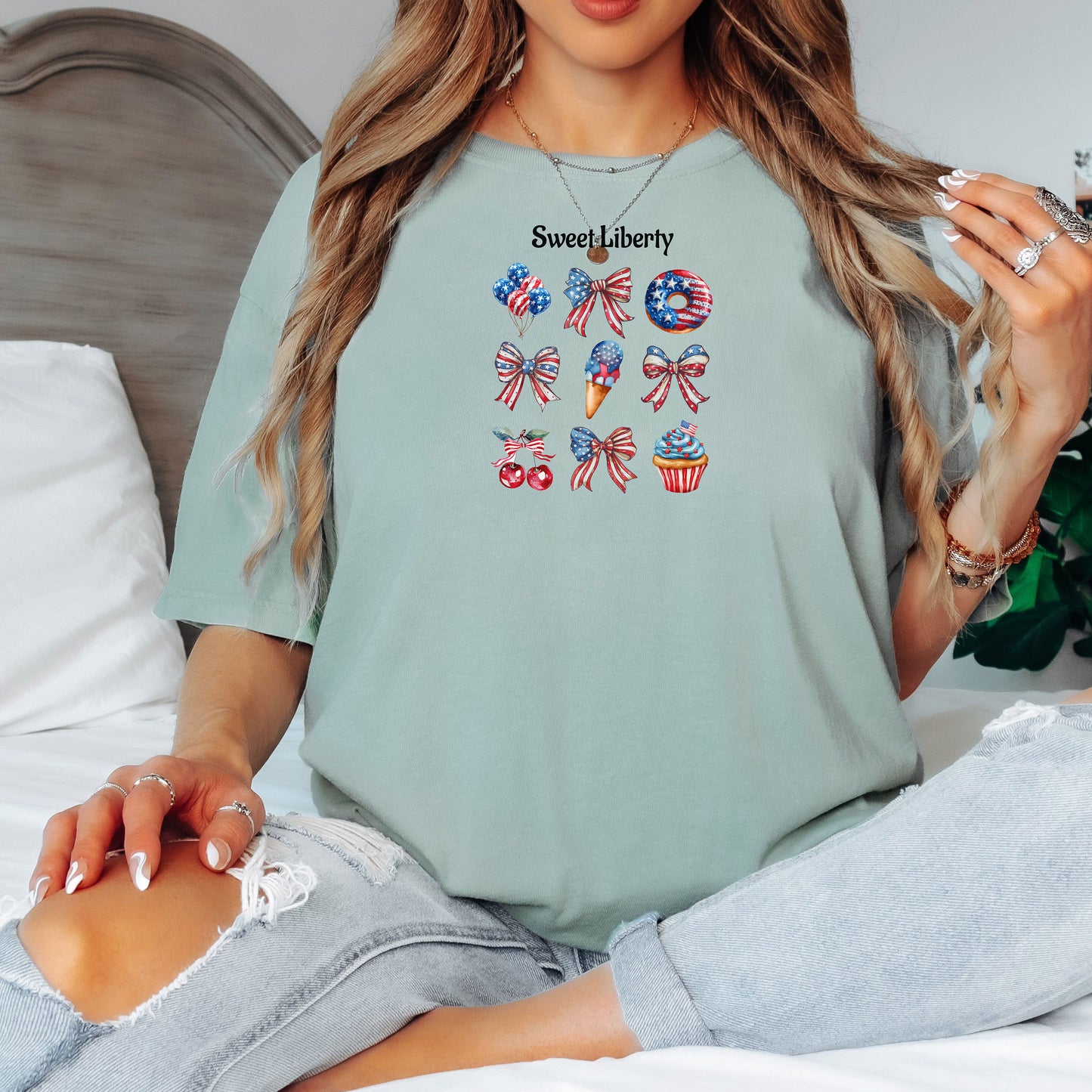Bay t-shirt featuring a festive 'Sweet Liberty' design with patriotic icons including bows, cherries, a donut, ice cream cone, and cupcake decorated in red, white, and blue stars and stripes. Fun, colorful 4th of July and summer celebration shirt perfect for parties, barbecues, and casual wear.