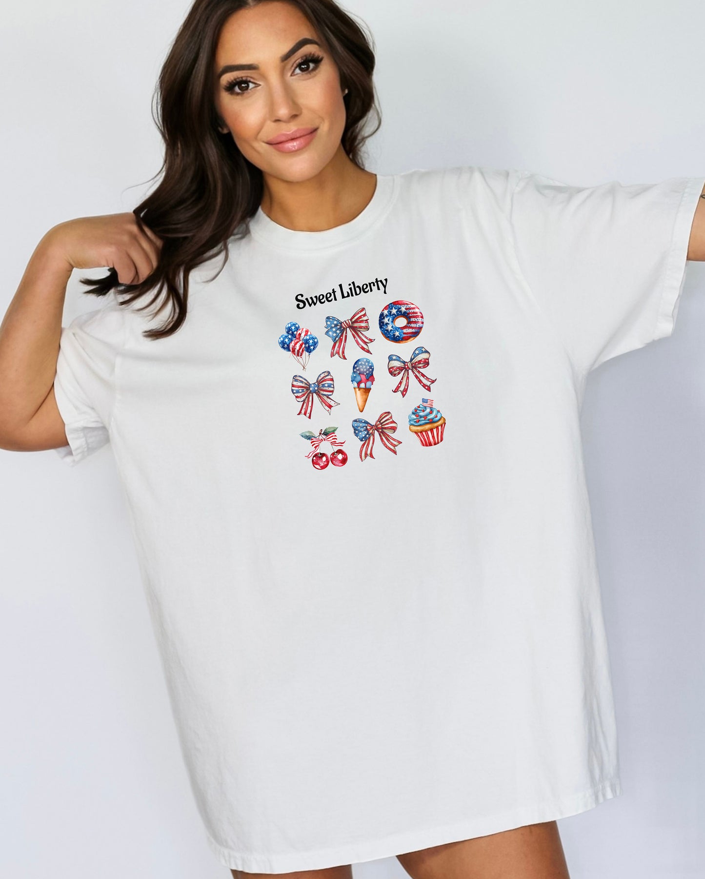 White t-shirt featuring a festive 'Sweet Liberty' design with patriotic icons including bows, cherries, a donut, ice cream cone, and cupcake decorated in red, white, and blue stars and stripes. Fun, colorful 4th of July and summer celebration shirt perfect for parties, barbecues, and casual wear.