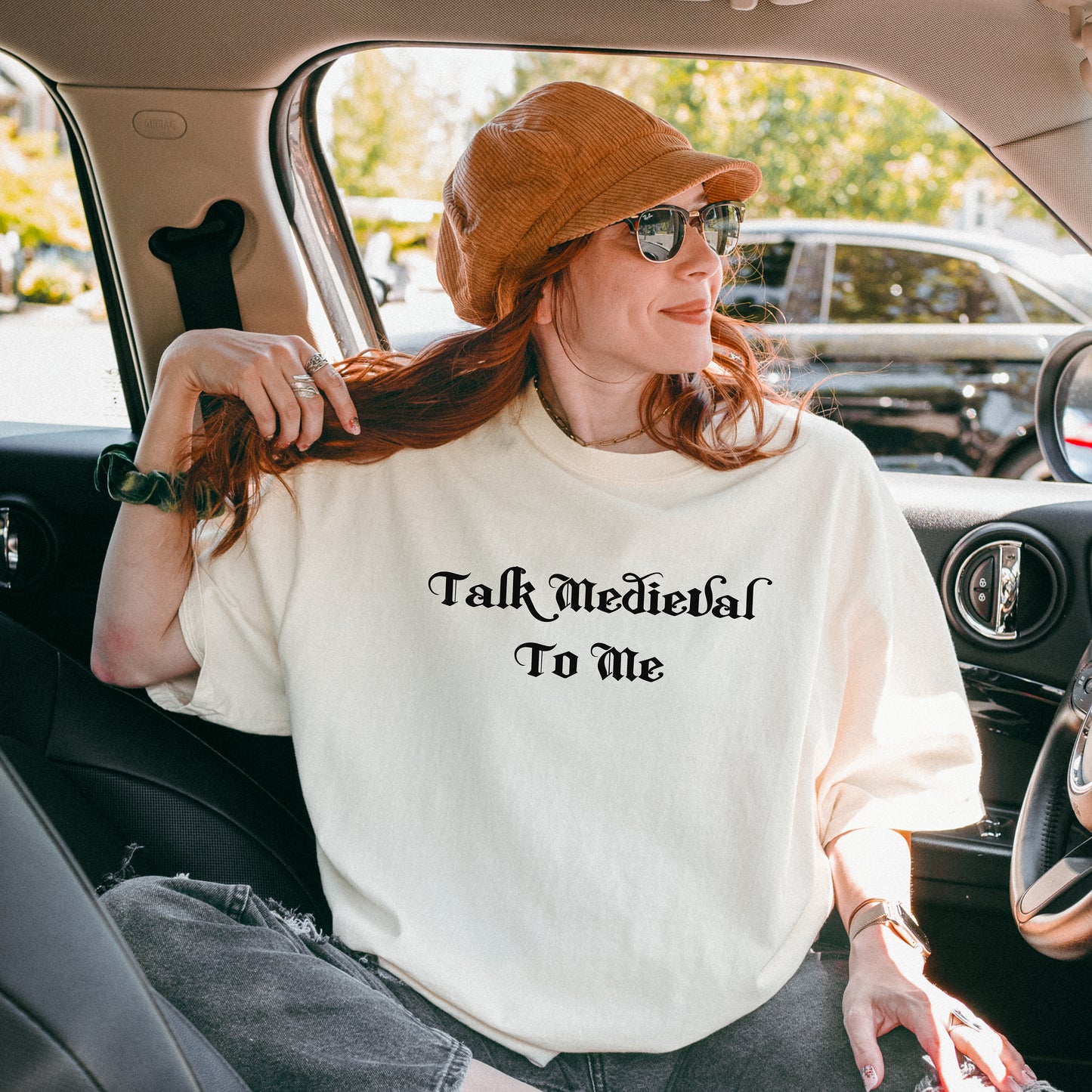 Ivory T-shirt featuring the phrase “Talk Medieval To Me” in a bold, Gothic-style blackletter font. Perfect for Renaissance Faire lovers, history buffs, and medieval festival goers who enjoy witty and playful designs that show off their love for knights, castles, and all things medieval.
