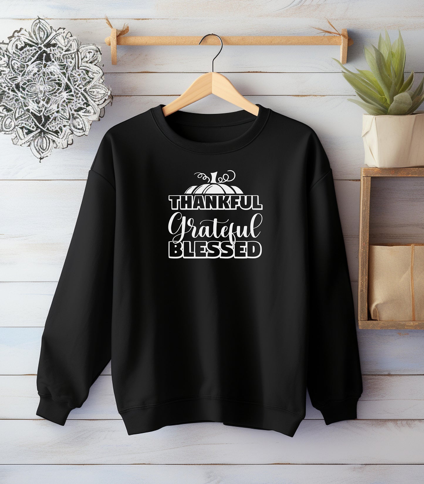 A “Thankful Grateful Blessed” Thanksgiving sweatshirt, featuring a festive pumpkin graphic against a wooden shiplap wall.