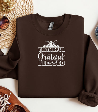 A “Thankful Grateful Blessed” Thanksgiving sweatshirt, featuring a festive pumpkin graphic, styled for cozy fall, autumn outfits and Thanksgiving celebrations