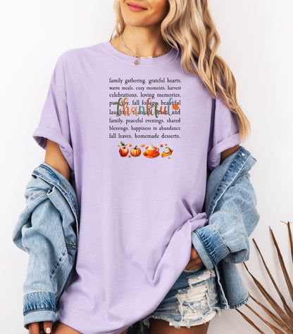 Person wearing an Orchid T-shirt with a festive “Thankful” harvest-themed design featuring fall words like family gathering, grateful hearts, cozy moments, and homemade desserts, with autumn illustrations of an apple, pumpkin, pie, and fall leaves. A warm and cheerful tee perfect for Thanksgiving, family gatherings, or celebrating the fall season.