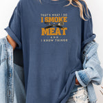 That's What I Do, I Smoke Meat & I Know Things T-shirt featuring bold text in yellow and white with crossed grilling tools at the center. Printed on a denim unisex tee, this fun BBQ-themed design is perfect for grill masters and smoking enthusiasts. Ideal for Father’s Day, cookouts, and casual wear for those proud of their grilling skills and witty sense of humor.