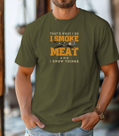 That's What I Do, I Smoke Meat & I Know Things T-shirt featuring bold text in yellow and white with crossed grilling tools at the center. Printed on a hemp unisex tee, this fun BBQ-themed design is perfect for grill masters and smoking enthusiasts. Ideal for Father’s Day, cookouts, and casual wear for those proud of their grilling skills and witty sense of humor.