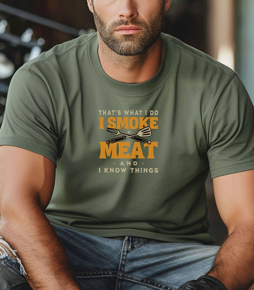 That's What I Do, I Smoke Meat & I Know Things T-shirt featuring bold text in yellow and white with crossed grilling tools at the center. Printed on a moss unisex tee, this fun BBQ-themed design is perfect for grill masters and smoking enthusiasts. Ideal for Father’s Day, cookouts, and casual wear for those proud of their grilling skills and witty sense of humor.