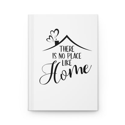 White hardcover journal with black text 'There is no place like home' and a house illustration on a white background
