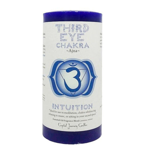 Third Eye Chakra pillar candle labeled "Ajna" with a deep indigo color and chakra symbol. Designed to enhance intuition and clarity, this candle is ideal for meditation, chakra rebalancing, and relaxation. Features a fragrance blend of jasmine and vetiver. Label includes affirmations and guidance for use in spiritual or sacred spaces. Crystal Journey Candles branding on bottom.