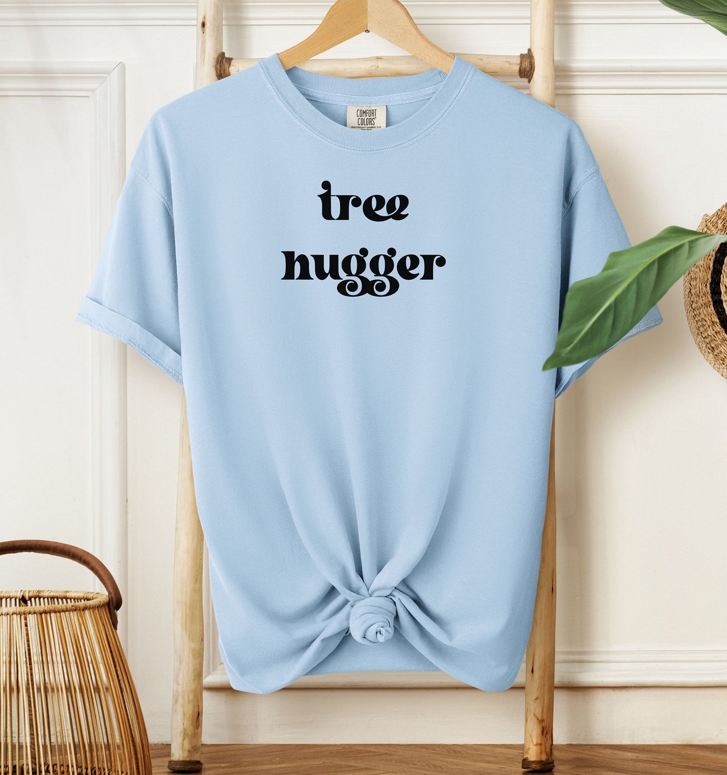 Tree Hugger T-shirt featuring bold retro-style black lettering on a chambray light blue unisex Comfort Colors tee. Perfect for nature lovers, environmentalists, and eco-conscious outdoor enthusiasts who appreciate a vintage vibe while showing their love for trees, conservation, and the planet.