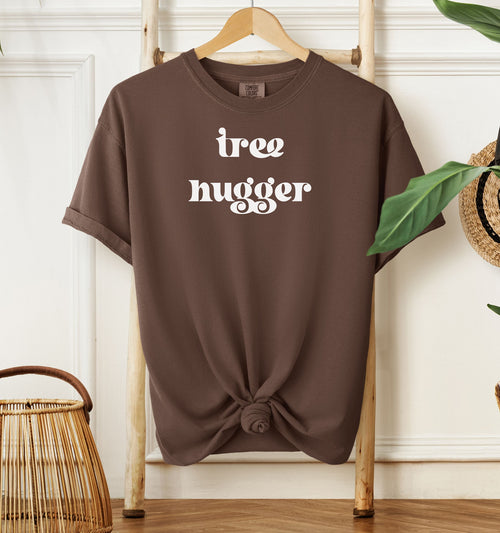 Tree Hugger T-shirt featuring bold retro-style white lettering on an espresso unisex Comfort Colors tee. Perfect for nature lovers, environmentalists, and eco-conscious outdoor enthusiasts who appreciate a vintage vibe while showing their love for trees, conservation, and the planet.