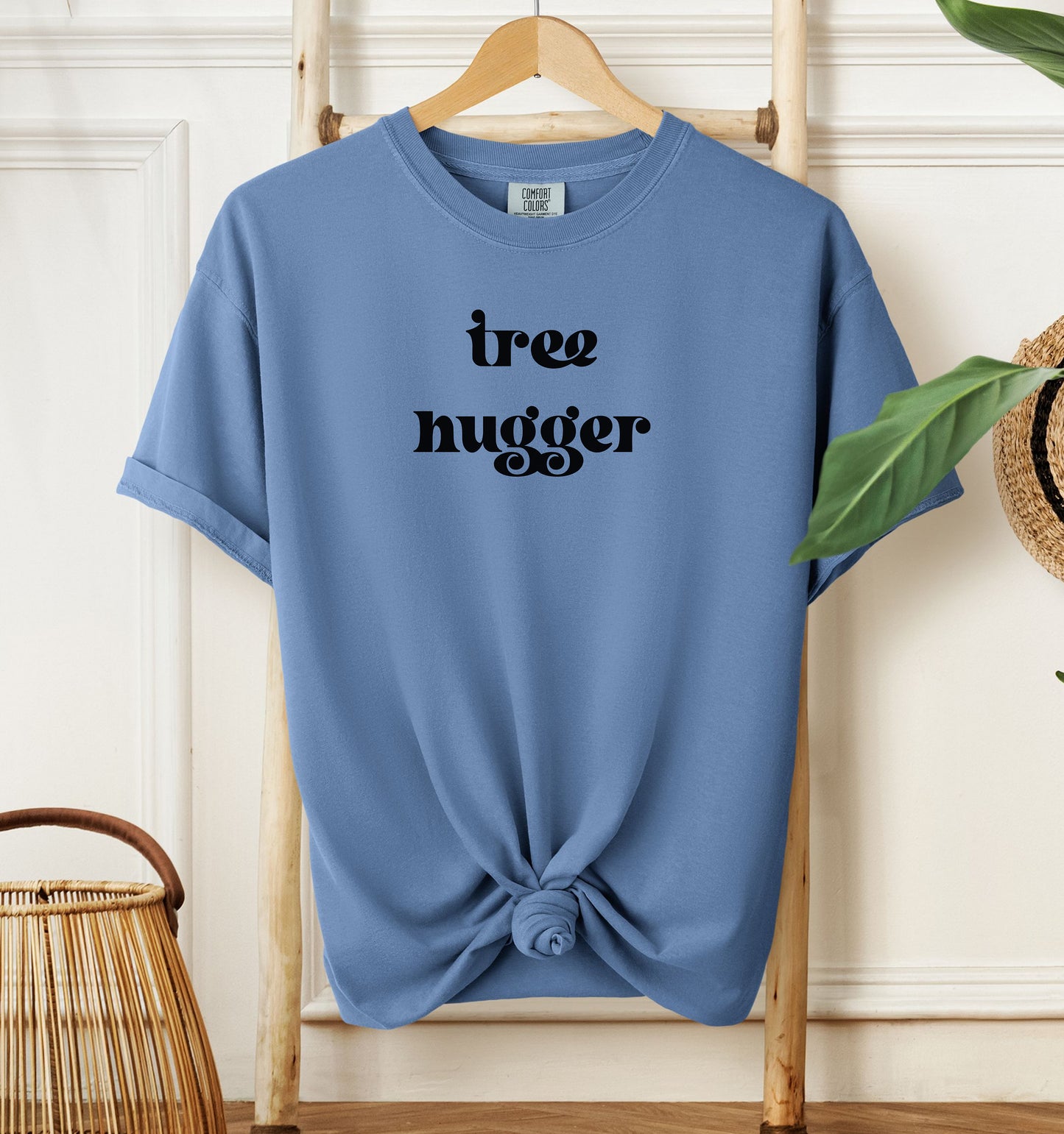 Tree Hugger T-shirt featuring bold retro-style black lettering on a washed denim unisex Comfort Colors tee. Perfect for nature lovers, environmentalists, and eco-conscious outdoor enthusiasts who appreciate a vintage vibe while showing their love for trees, conservation, and the planet.