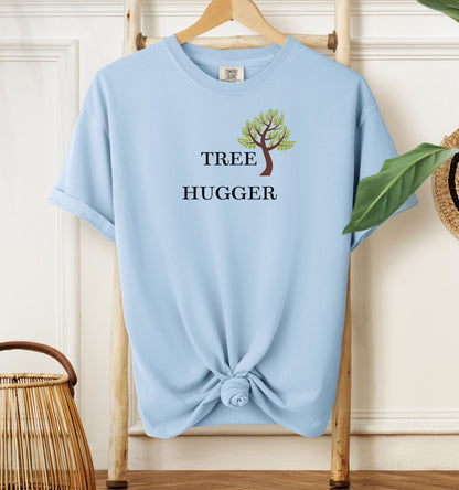 Tree Hugger T-shirt featuring a simple nature-inspired design with a brown and green tree graphic placed between the words Tree and Hugger in classic black font. Printed on a chambray light blue unisex Comfort Colors tee, this eco-friendly design is perfect for environmentalists, outdoor lovers, hikers, and anyone passionate about protecting nature and forests.