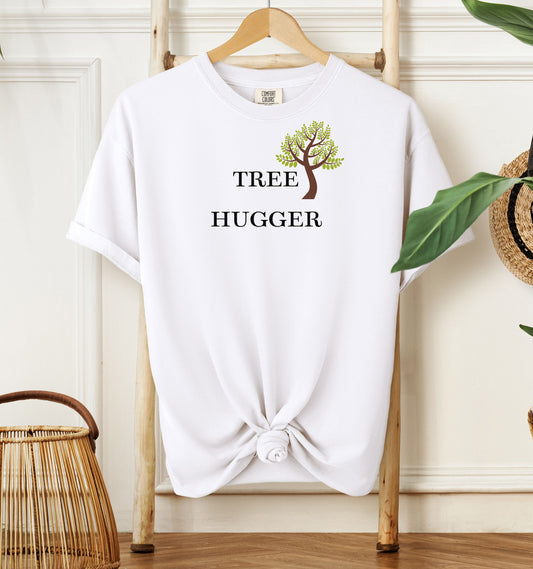Tree Hugger T-shirt featuring a simple nature-inspired design with a brown and green tree graphic placed between the words Tree and Hugger in classic black font. Printed on a white unisex Comfort Colors tee, this eco-friendly design is perfect for environmentalists, outdoor lovers, hikers, and anyone passionate about protecting nature and forests.