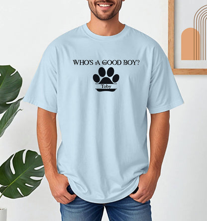 Man wearing a Chambray (light blue) t-shirt that reads “Who’s a Good Boy?” above a black paw print graphic with the name “Toby”. The shirt is a playful and heartwarming tribute to a beloved pet—perfect for dog Dads and dog lovers.
