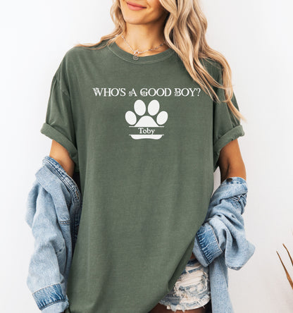 Woman wearing a Hemp color t-shirt that reads “Who’s a Good Boy?” above a white paw print graphic with the name “Toby”. The shirt is a playful and heartwarming tribute to a beloved pet—perfect for dog Moms and dog lovers.