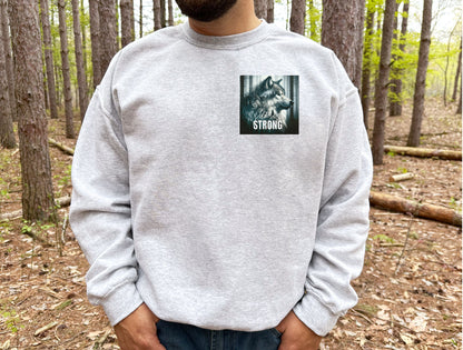 Ash Gildan sweatshirt featuring a “Wilderness Strong” design on the pocket area with a detailed illustration of a majestic wolf in a misty forest. The powerful graphic symbolizes resilience, strength, and connection to nature—ideal for outdoor lovers, wildlife fans, and those who embody the spirit of the wild.