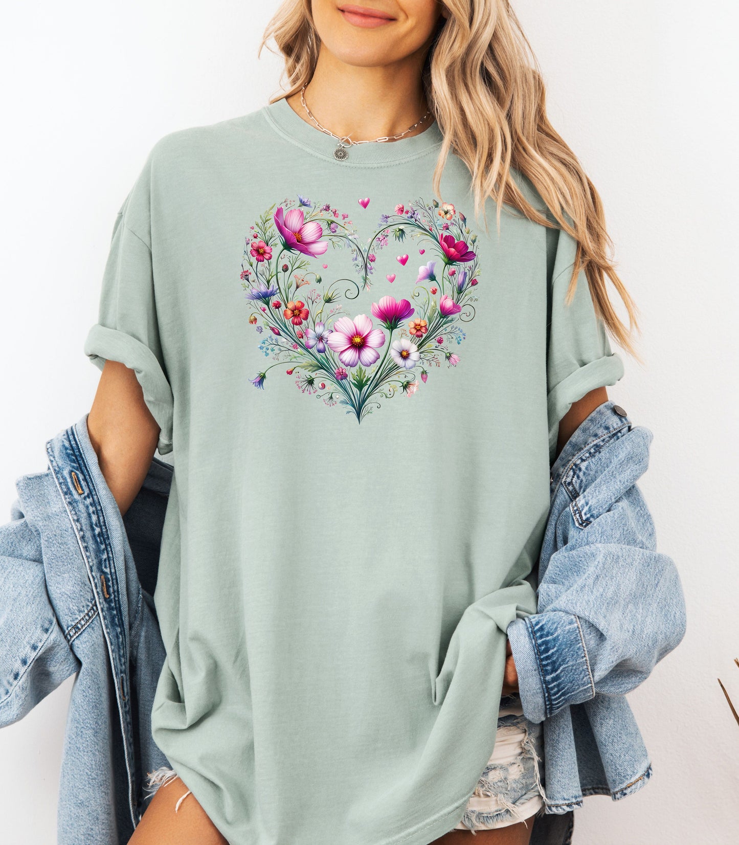 Person wearing a bay t-shirt with a wildflower boho heart design, standing against a white background.