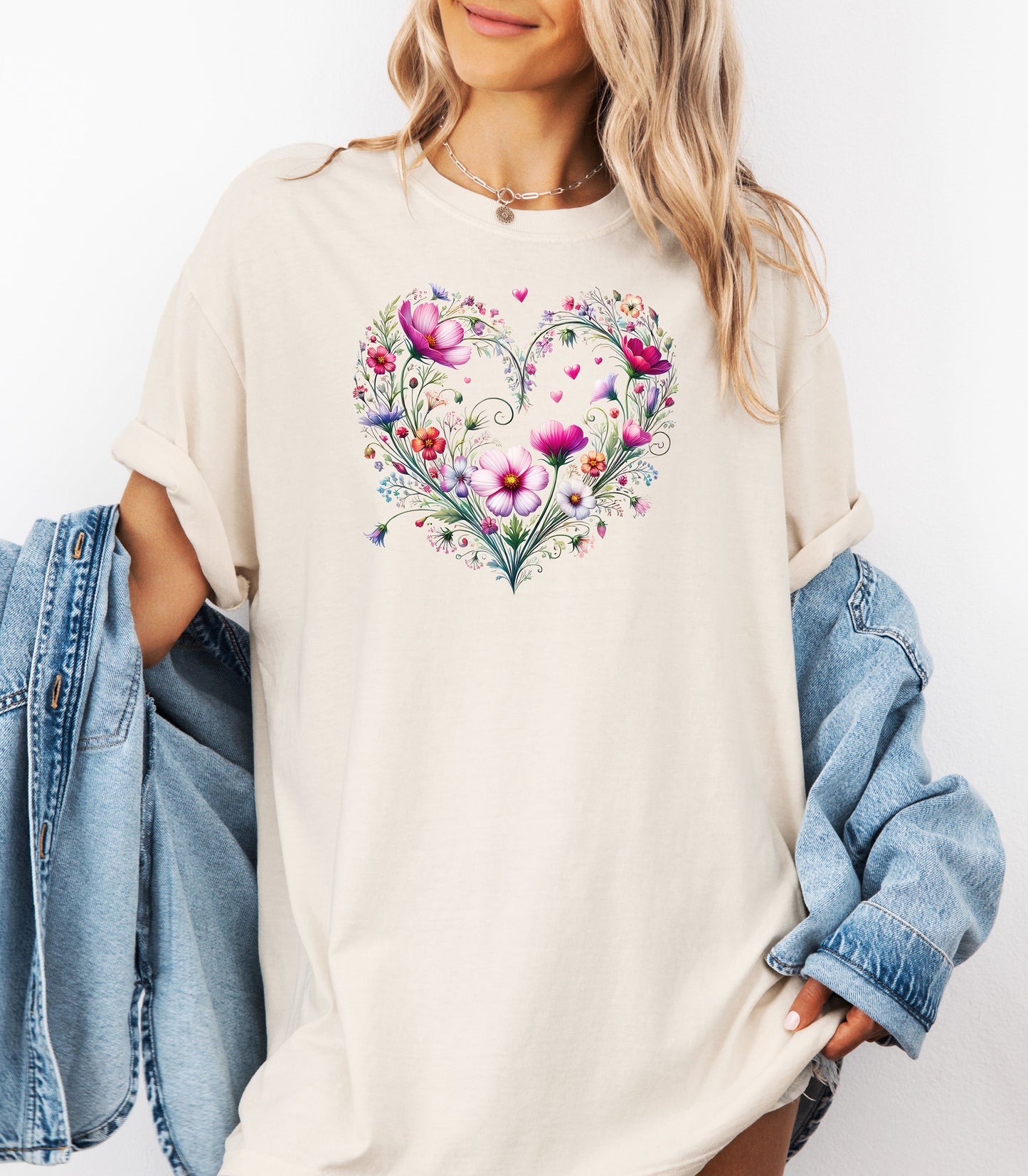 Person wearing an ivory t-shirt with a wildflower boho heart design, standing against a white background.